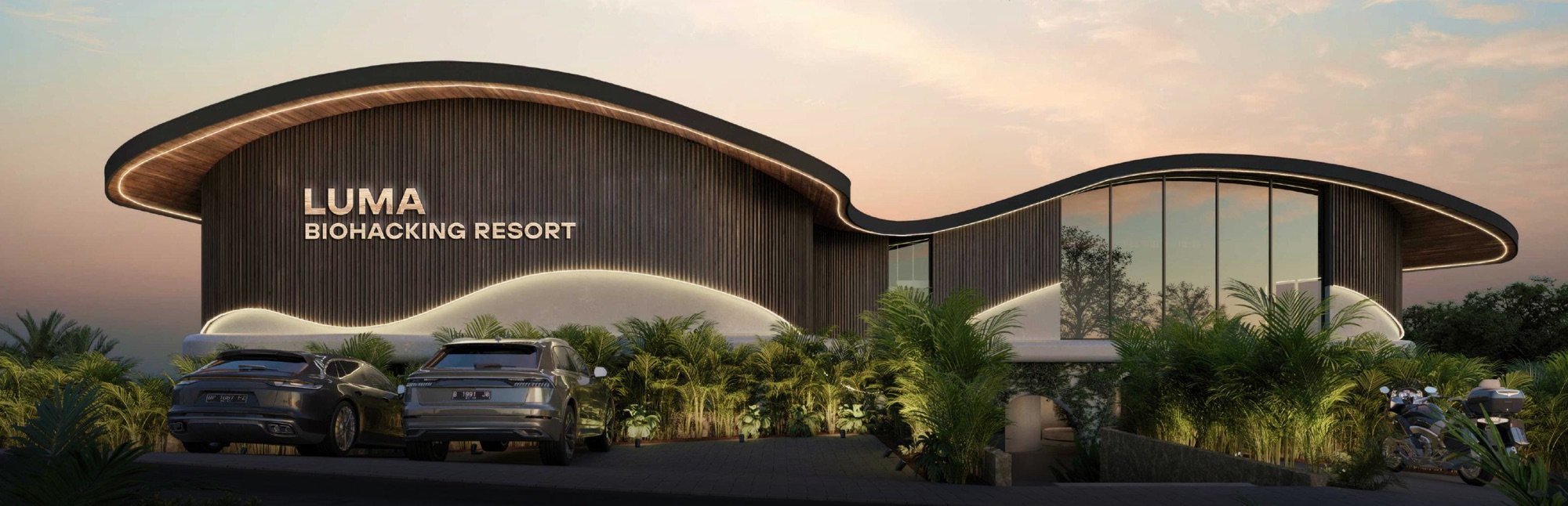 Luma Biohacking Resort at dusk — a wave-formed roof lit warm above the Uluwatu jungle