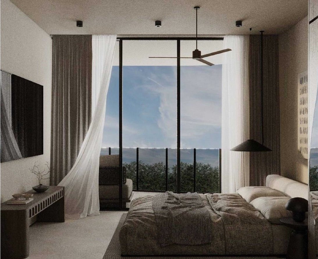 Studio bedroom opening onto a jungle-and-ocean view through full-height glass